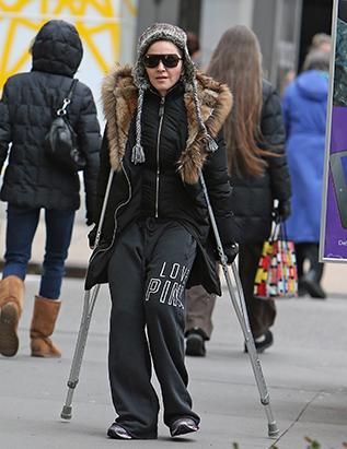 Madonna hobbles down the street on crutches